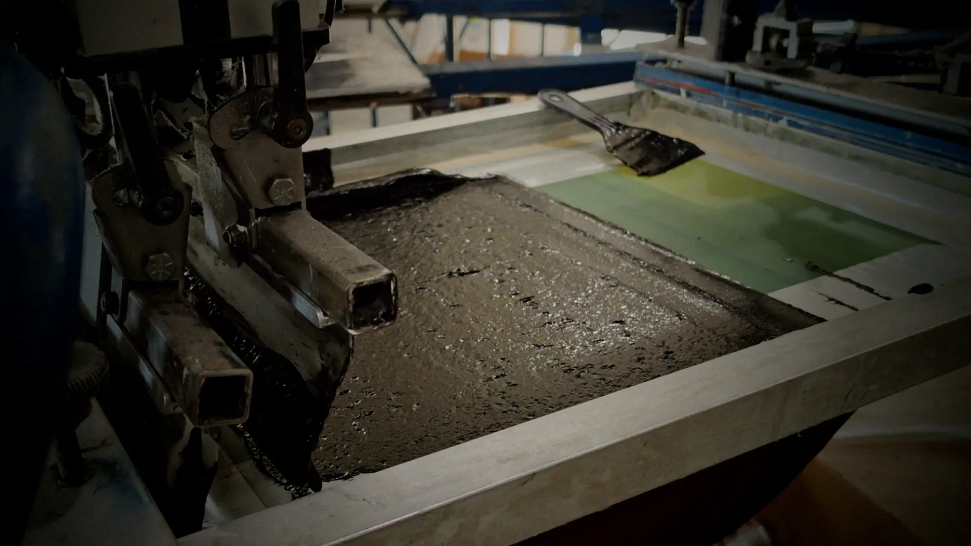 Squeegee pulling a print stroke on an M&R automatic screen printing press at French Press Custom