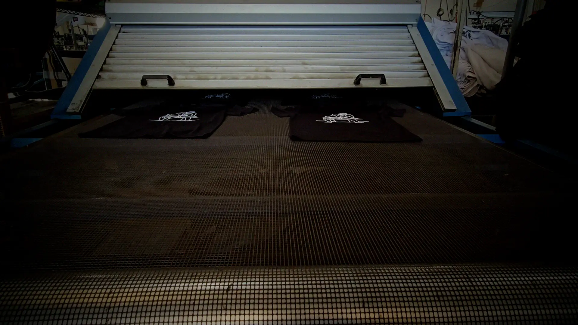Freshly cured black t-shirts coming off the conveyor dryer belt at French Press Custom